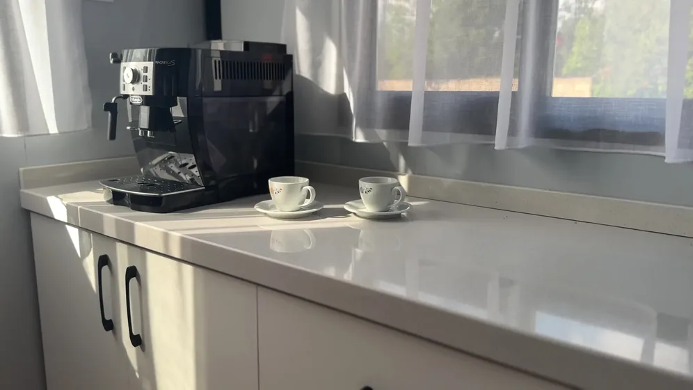 Kávovar a šálky na pracovní desce kuchyňské linky