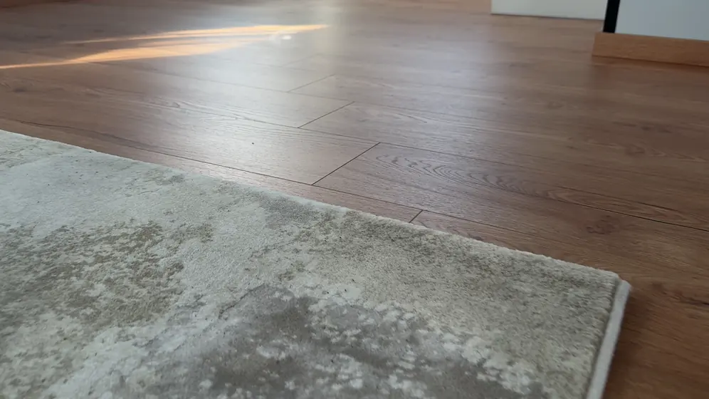Dřevěná podlaha a okraj koberce zblízka